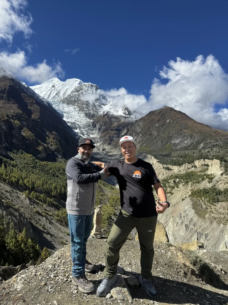 Two trekkers on a ridge above the Manang valley with snow peaks