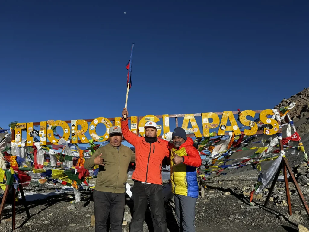 Trekkers celebrating at the Thorong La Pass sign at 5,416 m