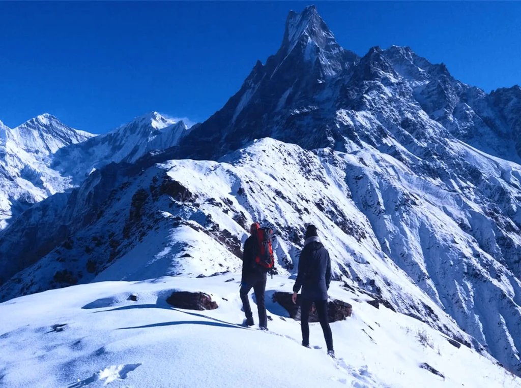 Two trekkers on the snowy Mardi Himal ridge below Machhapuchhre