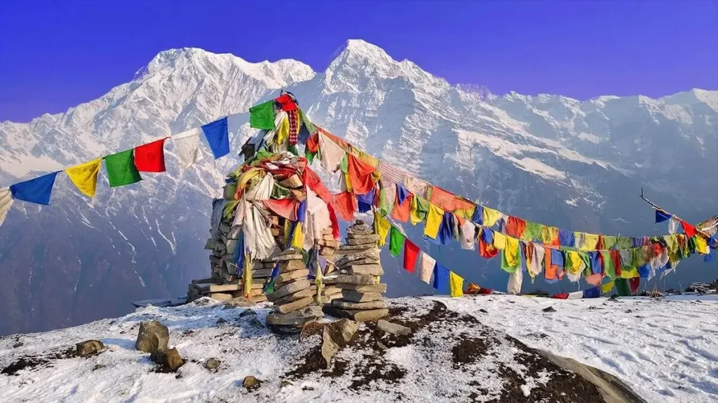 Prayer flags and a stone cairn in the snow with the Annapurna range behind