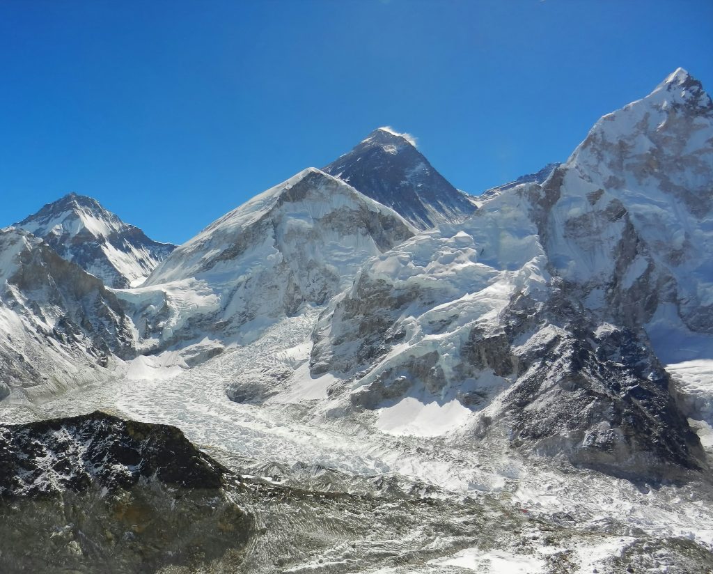 Everest's dark summit pyramid behind Nuptse above the Khumbu Glacier under a clear blue sky