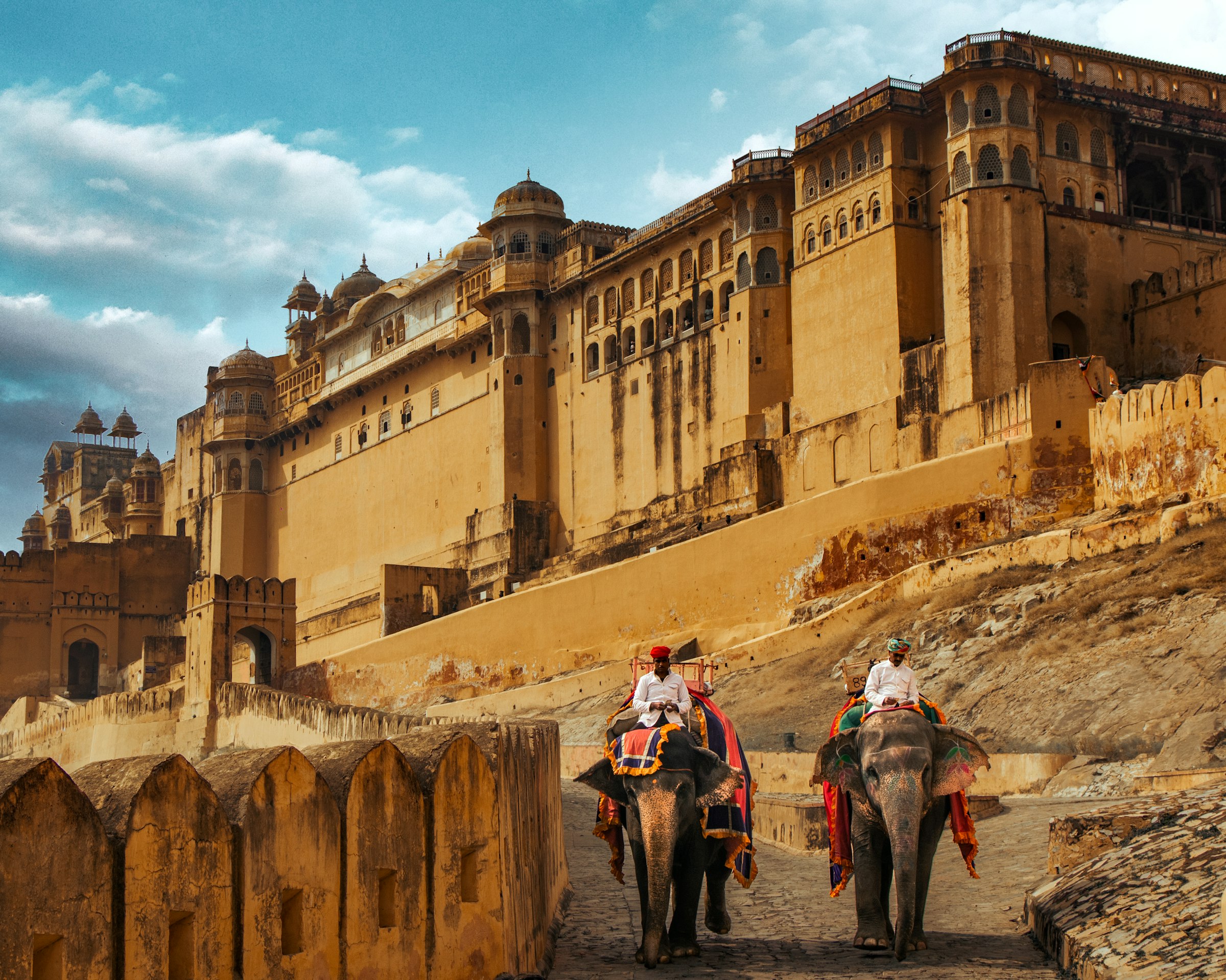 Decorated elephants carrying riders up the path below the golden walls of Amber Fort near Jaipur