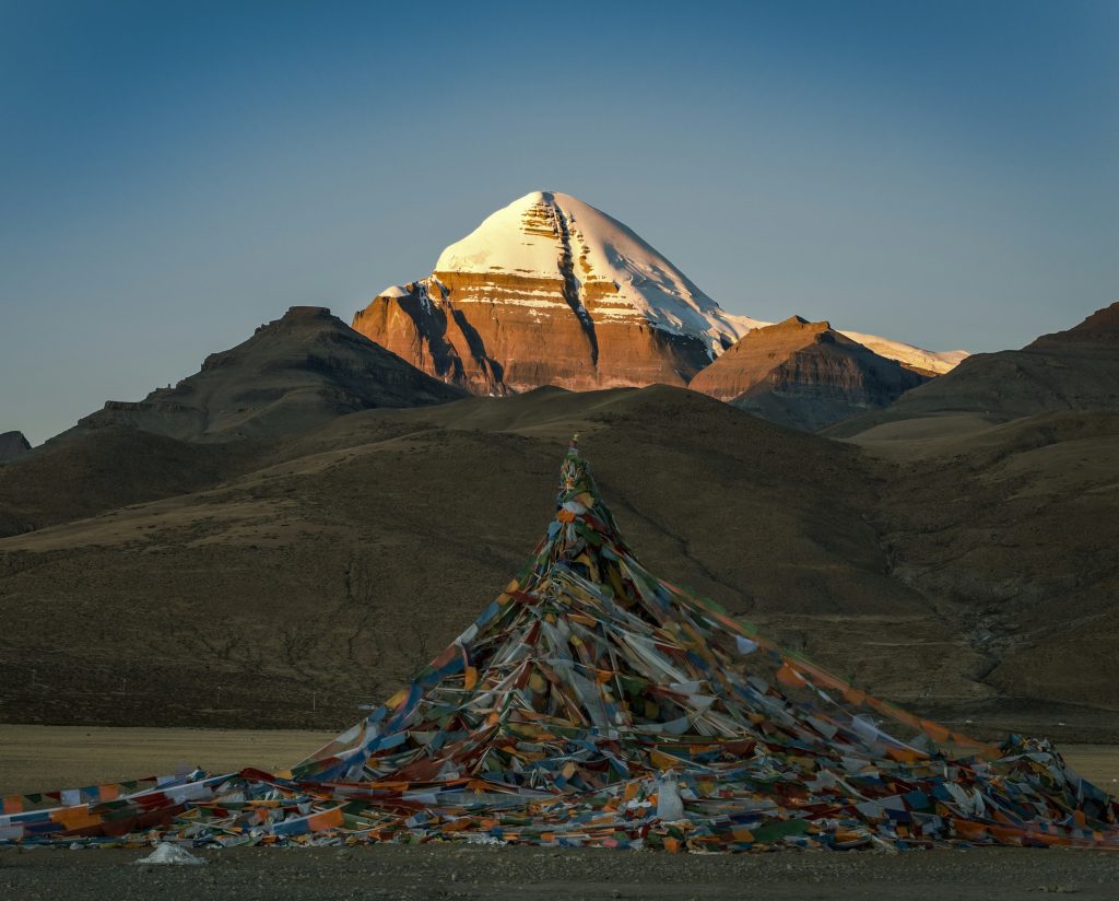 Mount Kailash glowing in early light behind a great mound of colourful prayer flags