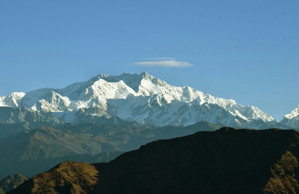 Broad snowy massif above dark blue foothills under a clear sky in the Kangchenjunga region