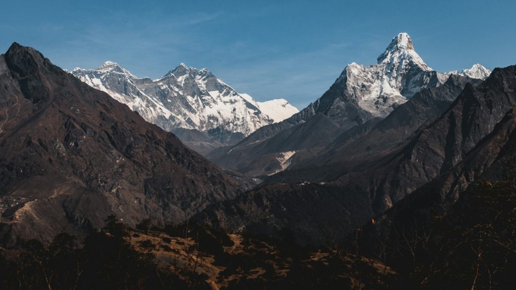Shadowed valley ridges leading to high snowy peaks of the Everest region with Ama Dablam on the right