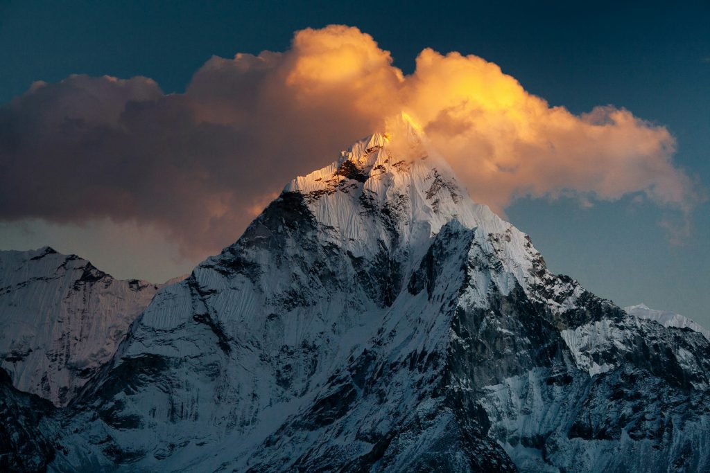 Ama Dablam's snowy summit lit by sunset beneath a glowing orange cloud