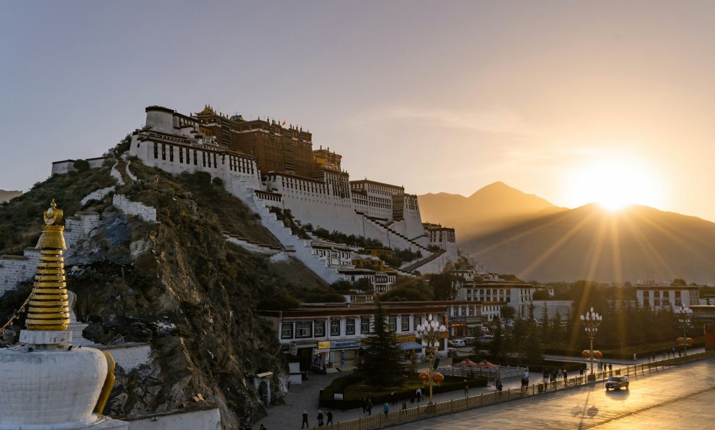 Potala Palace on its hill at sunset with a gilded chorten and street in the foreground