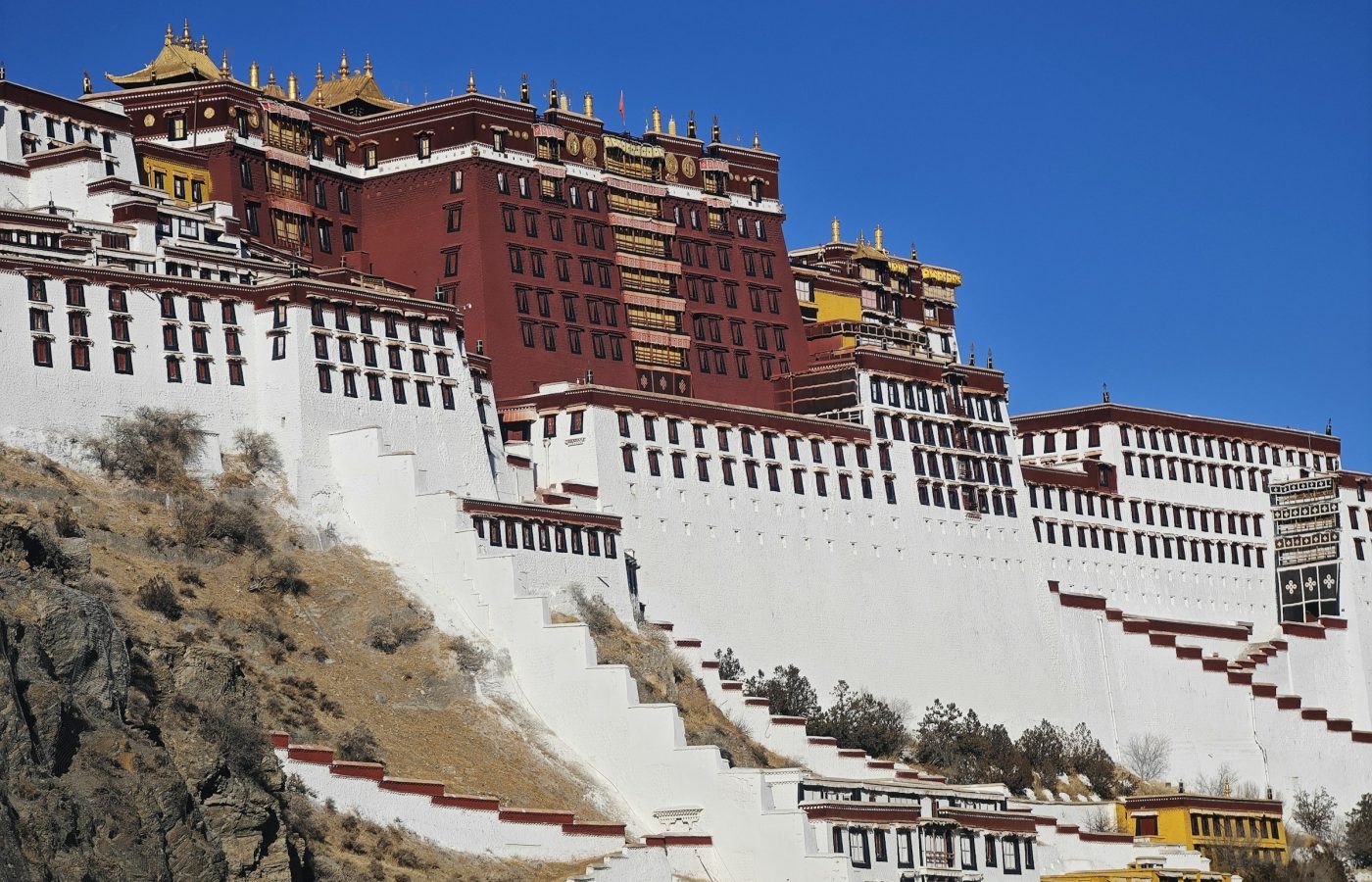 Potala Palace's red and white walls and zigzag stairways against a deep blue sky in Lhasa