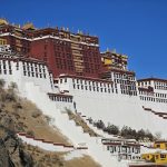 Potala Palace's red and white walls and zigzag stairways against a deep blue sky in Lhasa