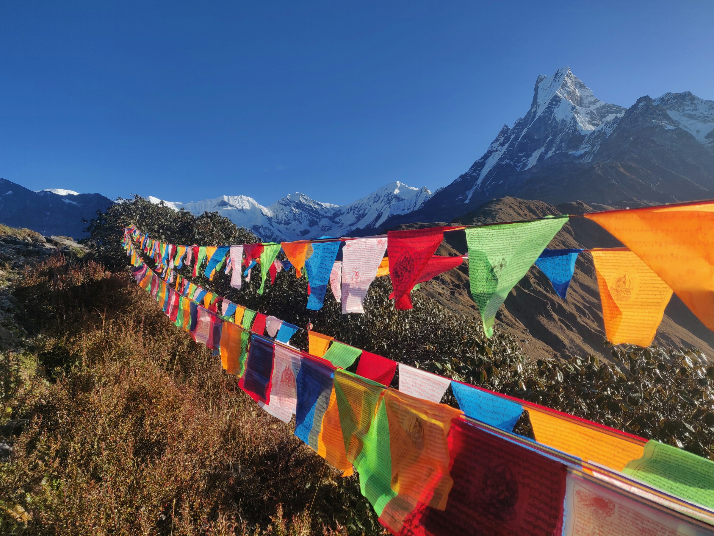 Long string of colourful prayer flags across a ridge with Machhapuchhre's fishtail peak beyond